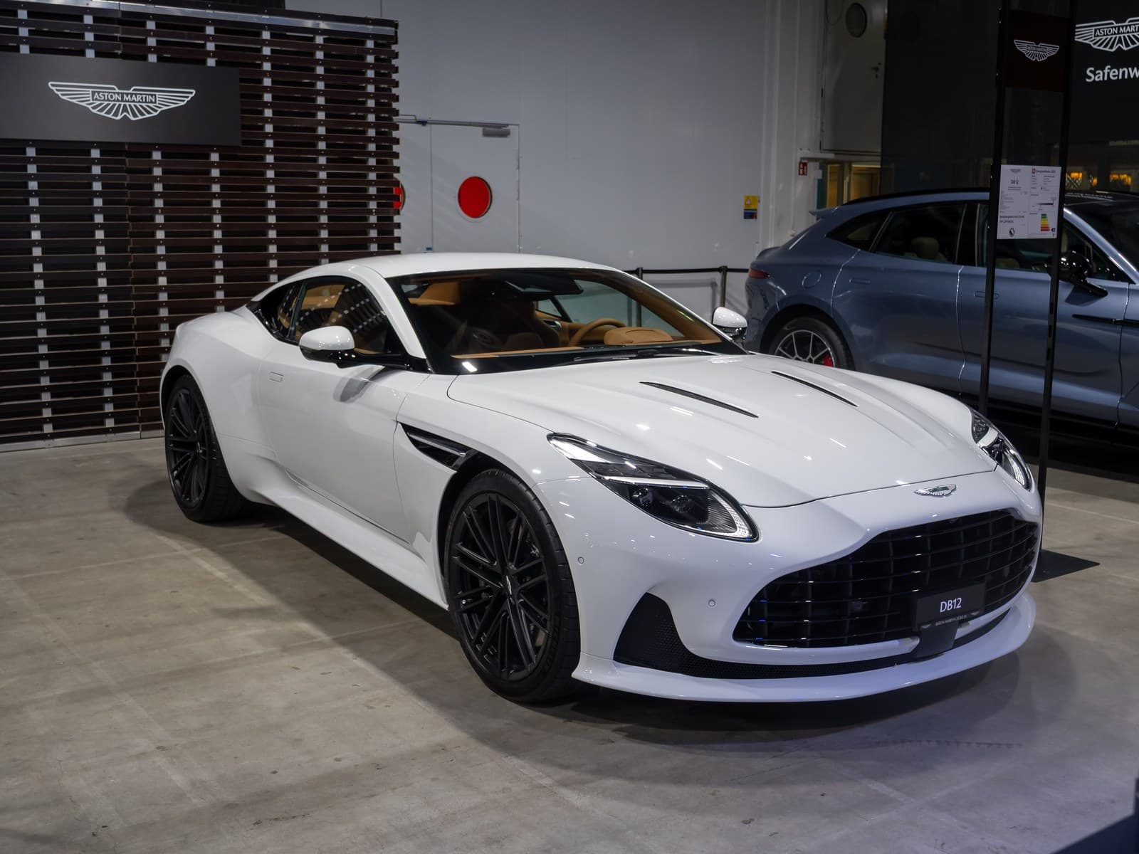 Aston Martin DB12 bianca, vista anteriore di tre quarti a un salone