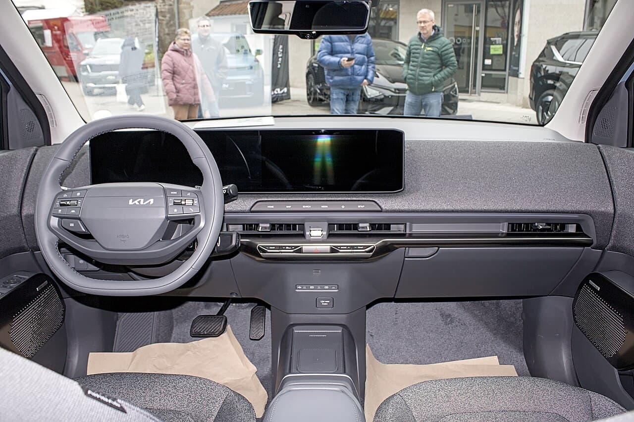 Kia EV2, plancia con doppio schermo panoramico e volante Kia, vista dal centro