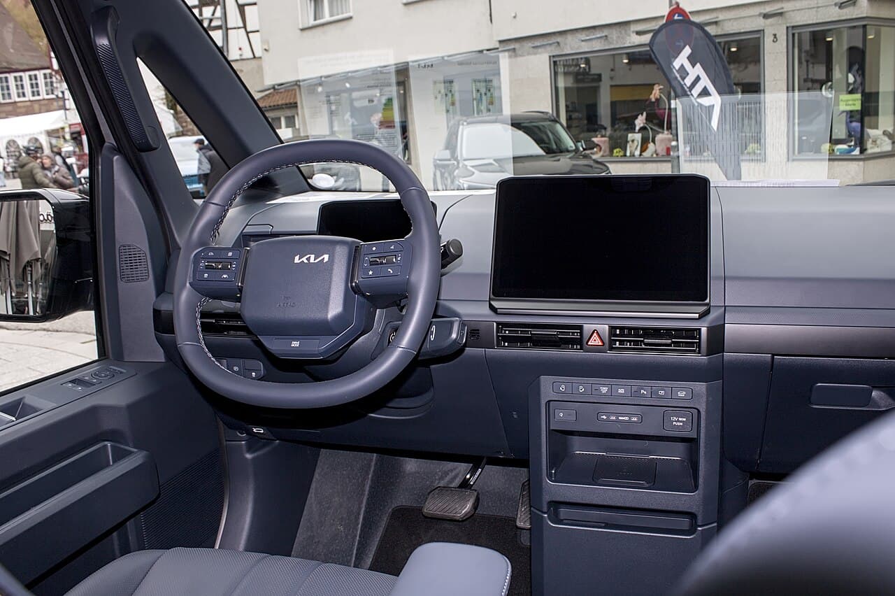 Kia PV5, posto di guida alto da furgone, con volante Kia e schermo verticale