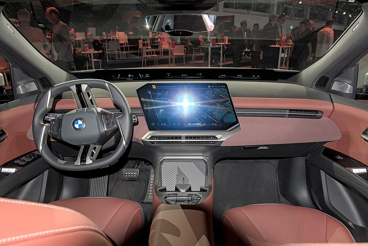 BMW iX3, plancia con schermo curvo e sedili in pelle marrone, vista dal centro