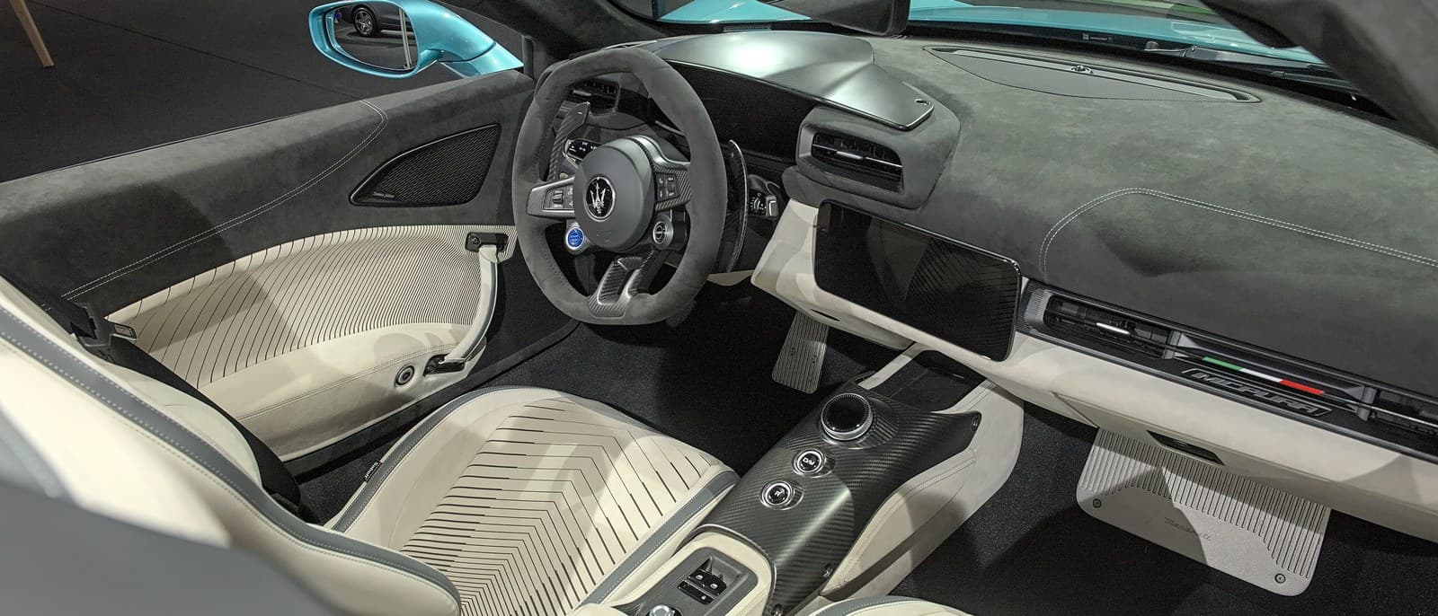 Interni della Maserati MCPura: volante in Alcantara, schermo centrale, console in carbonio e sedili chiari