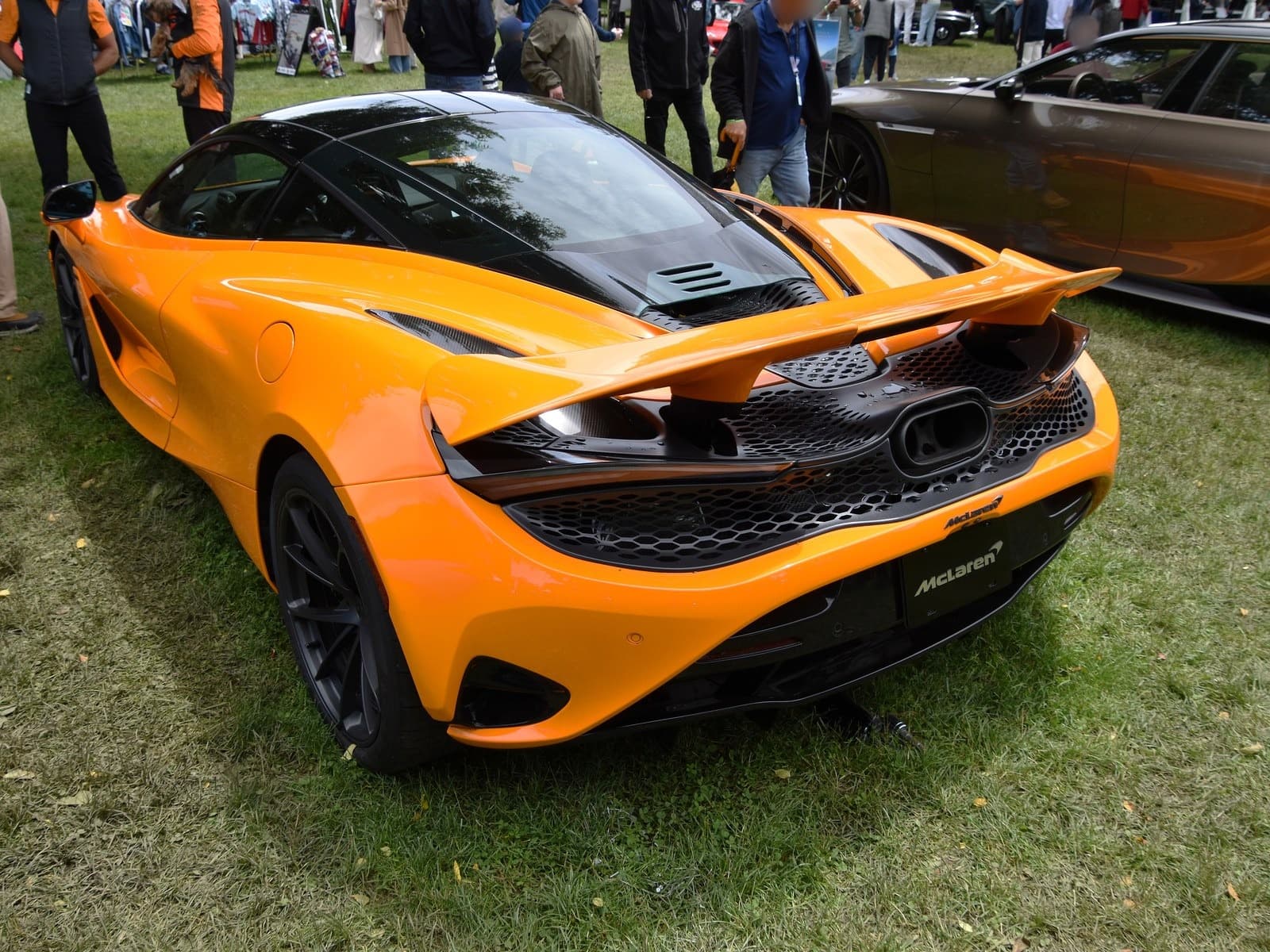 McLaren 750S arancione, vista posteriore di tre quarti su un prato