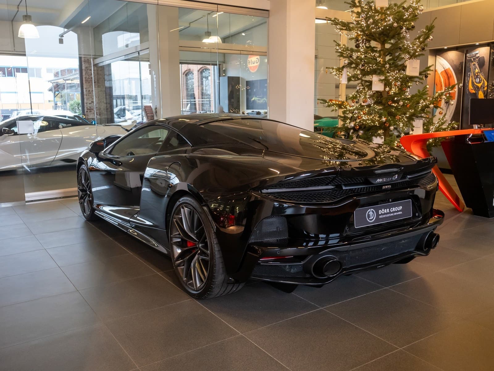 McLaren GTS nera, vista posteriore di tre quarti in un salone