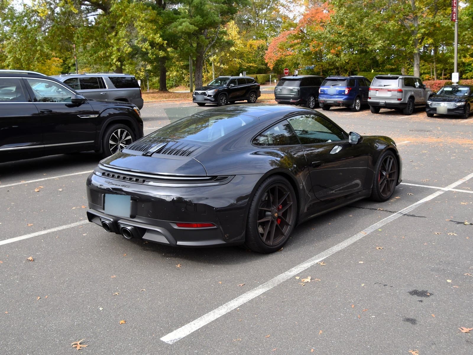 Porsche 911 Carrera GTS nera, vista posteriore di tre quarti in un parcheggio