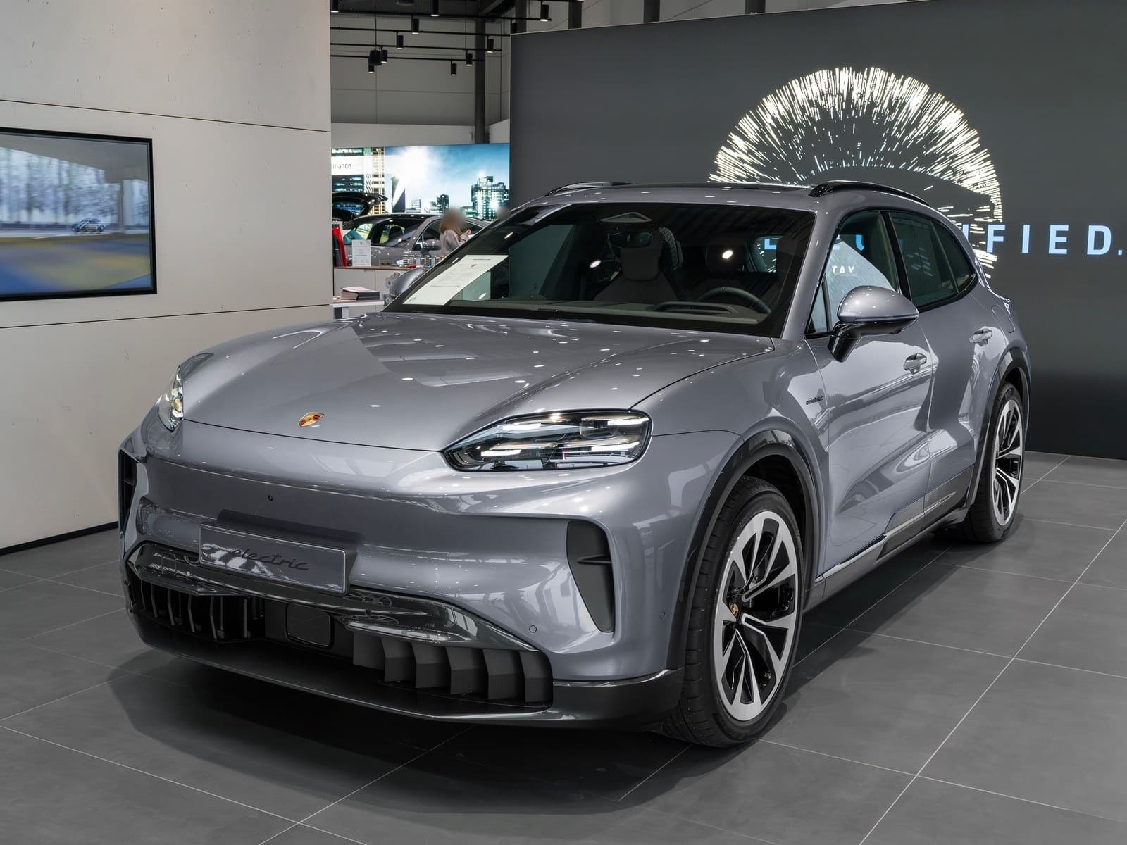 Porsche Cayenne Electric grigia, vista anteriore di tre quarti in un salone
