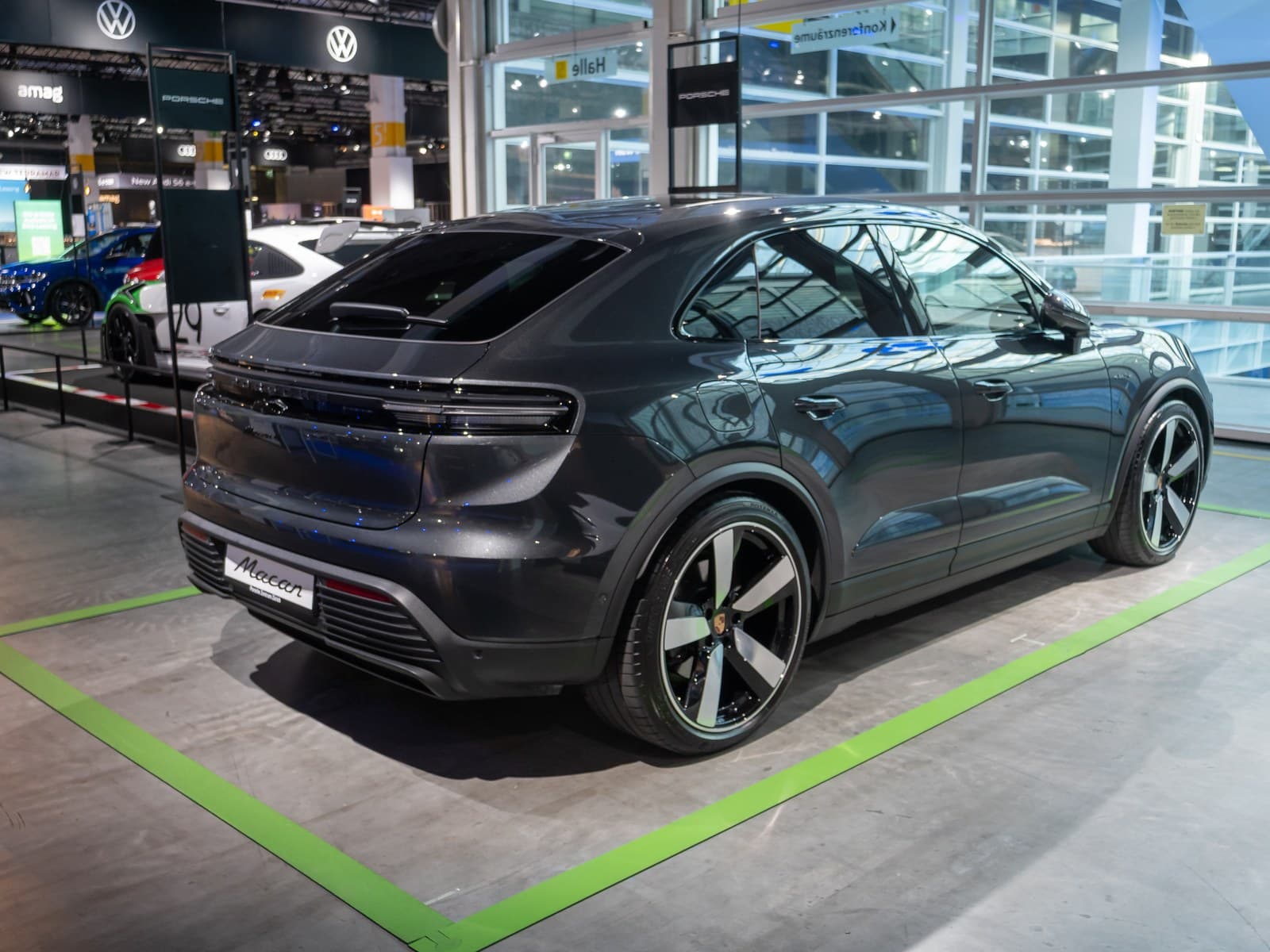 Porsche Macan elettrica grigio scuro, vista posteriore di tre quarti al salone