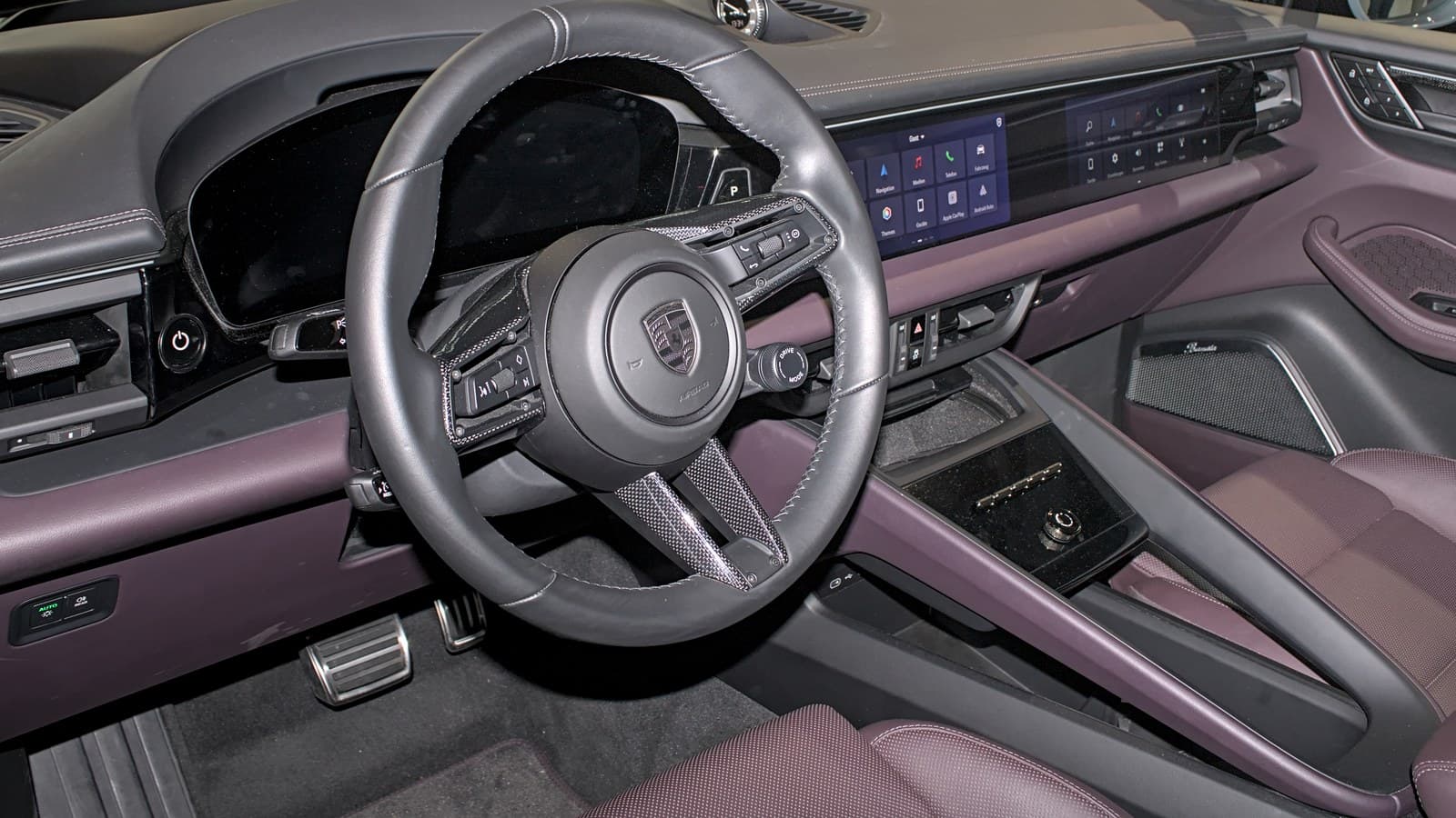 Plancia della Porsche Macan elettrica con volante e schermi, interni viola