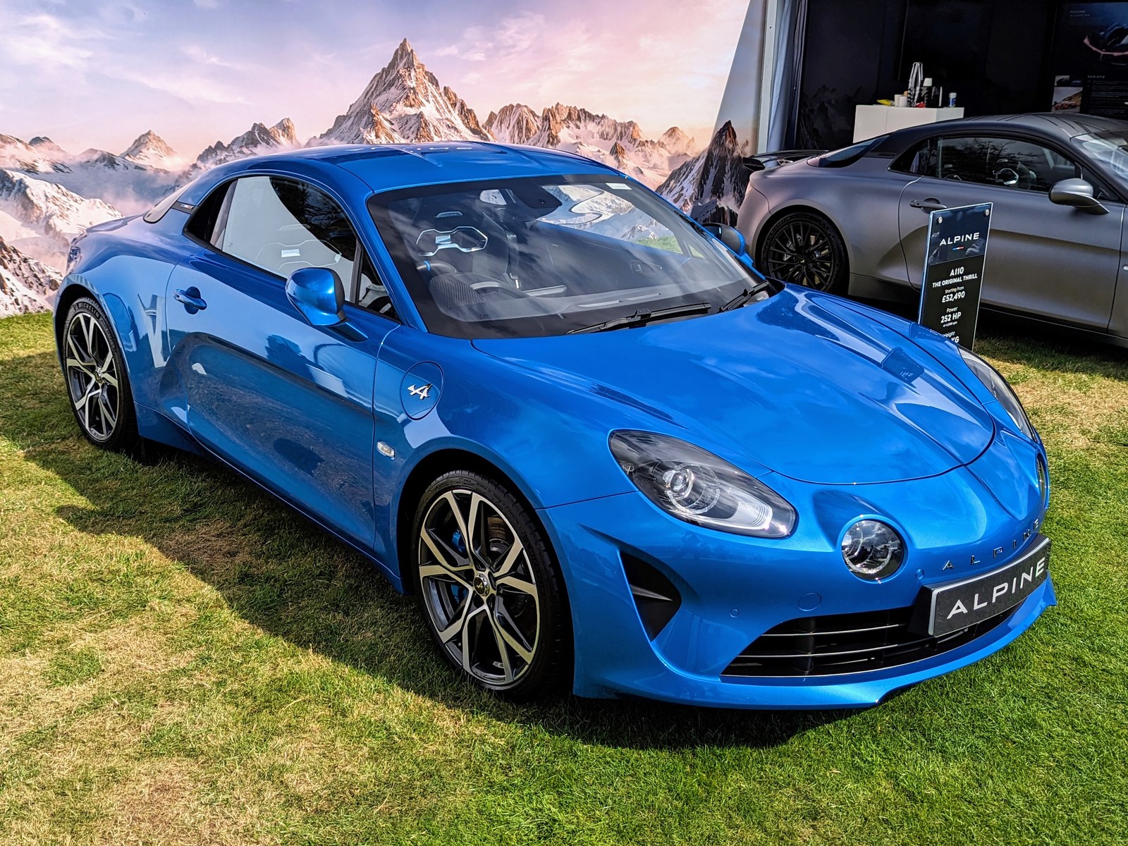 Alpine A110 blu, vista anteriore di tre quarti su un prato