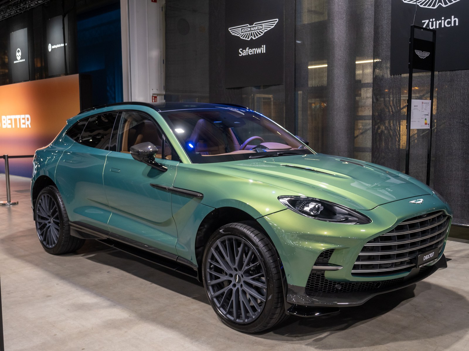 Aston Martin DBX707 verde, vista anteriore di tre quarti a un salone