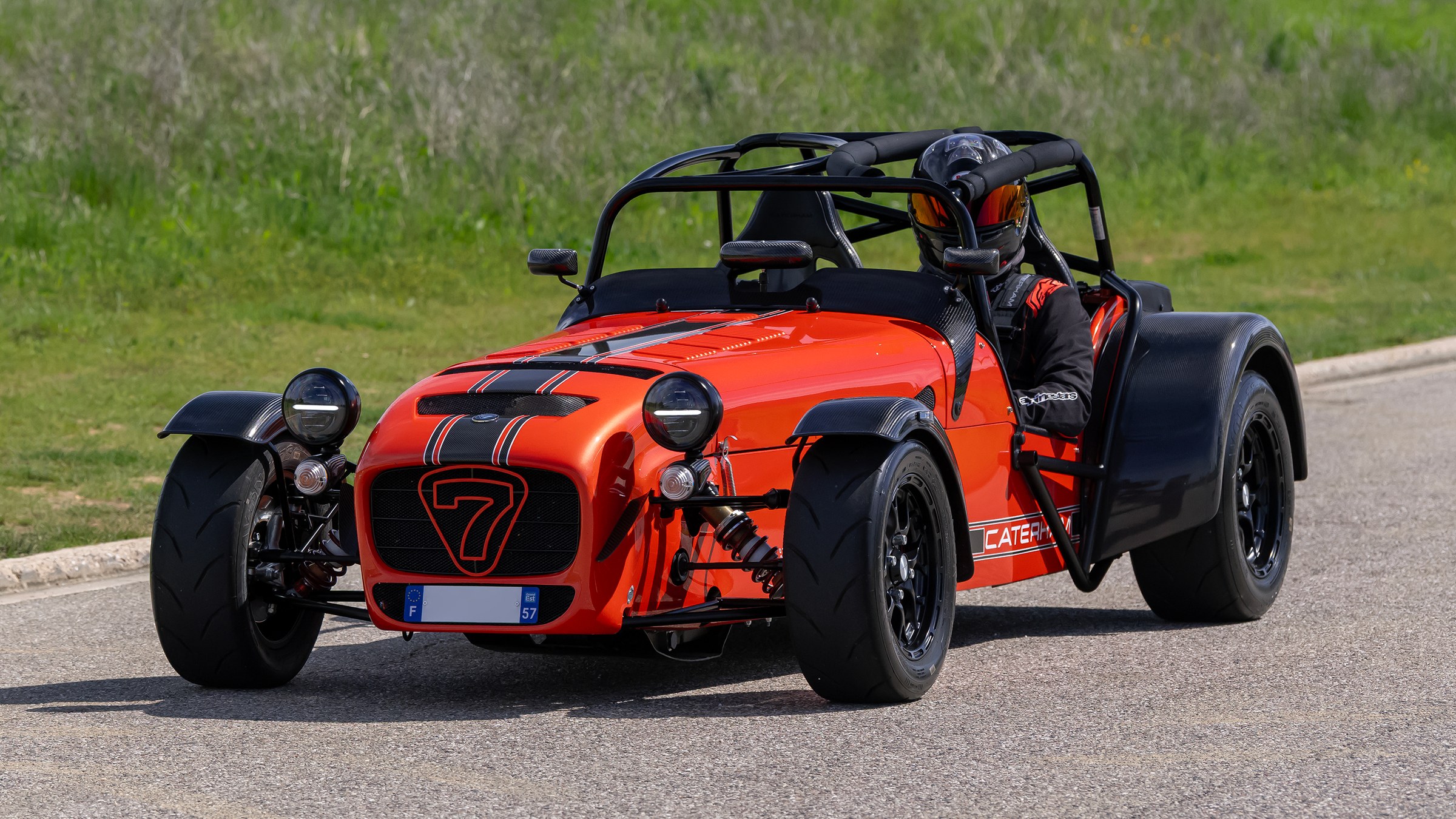 Caterham Seven 340 R arancione, vista anteriore di tre quarti in movimento su strada