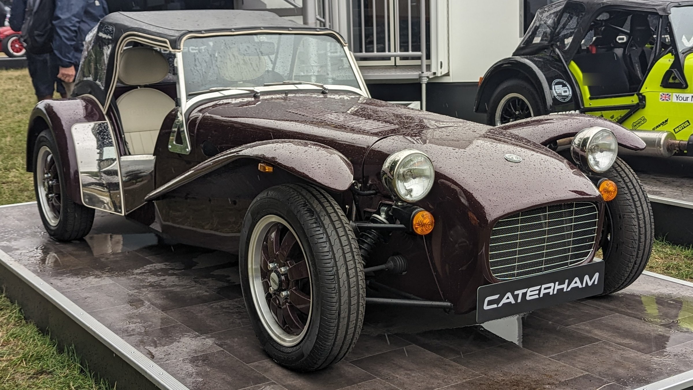 Caterham Super Seven 600 bordeaux con capote, vista anteriore di tre quarti sotto la pioggia