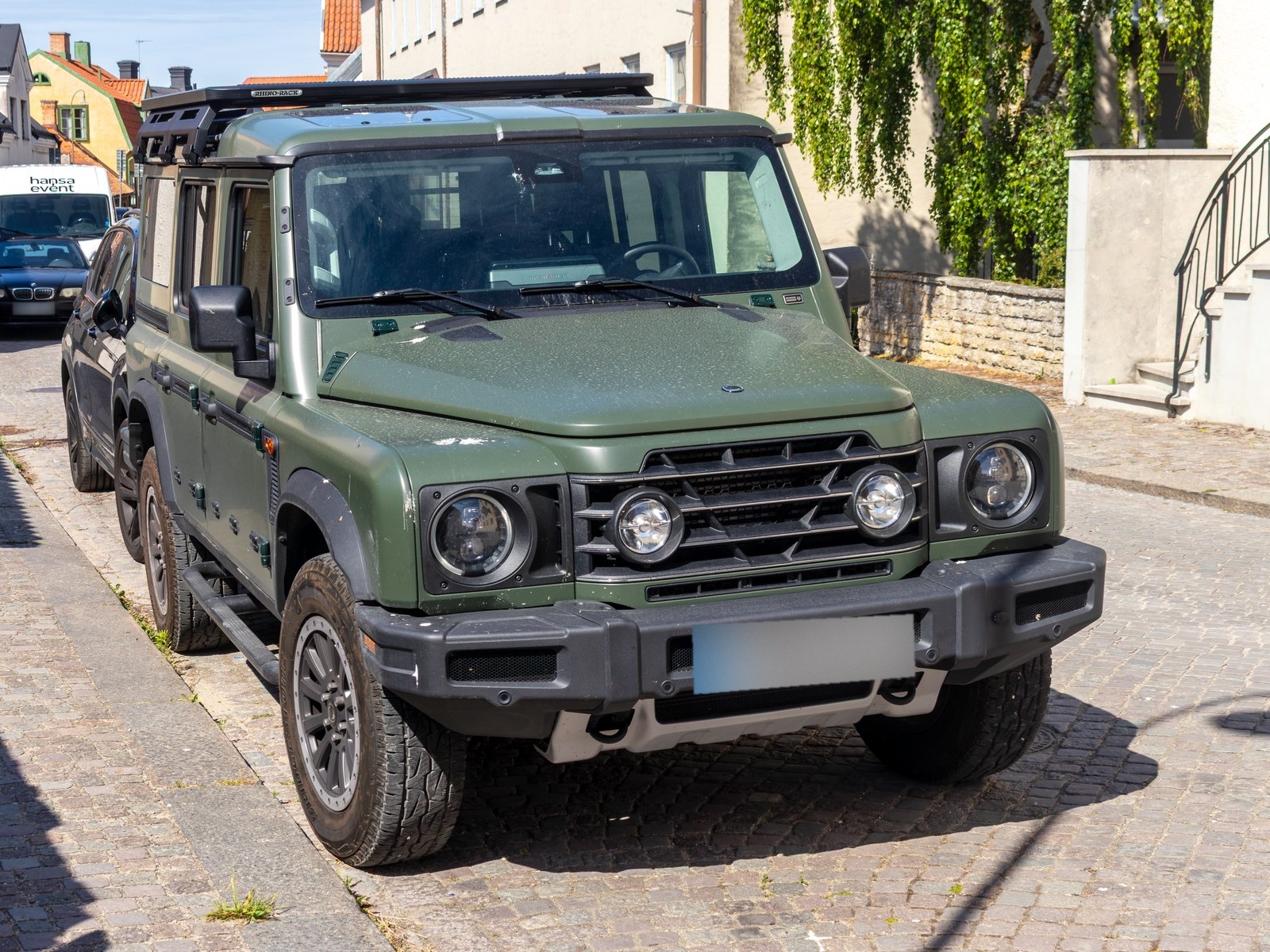 Ineos Grenadier Station Wagon verde oliva, vista anteriore di tre quarti in una via lastricata