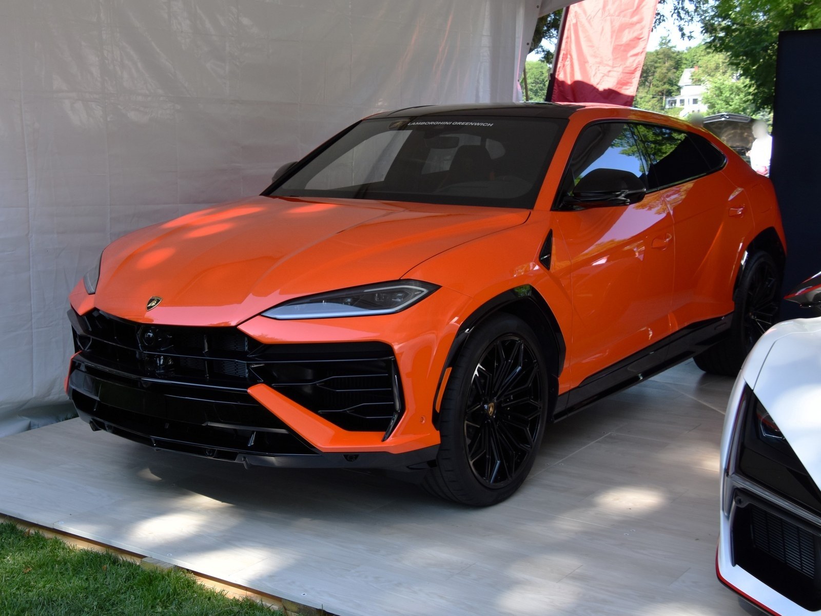Lamborghini Urus SE arancione, vista anteriore di tre quarti sotto un gazebo