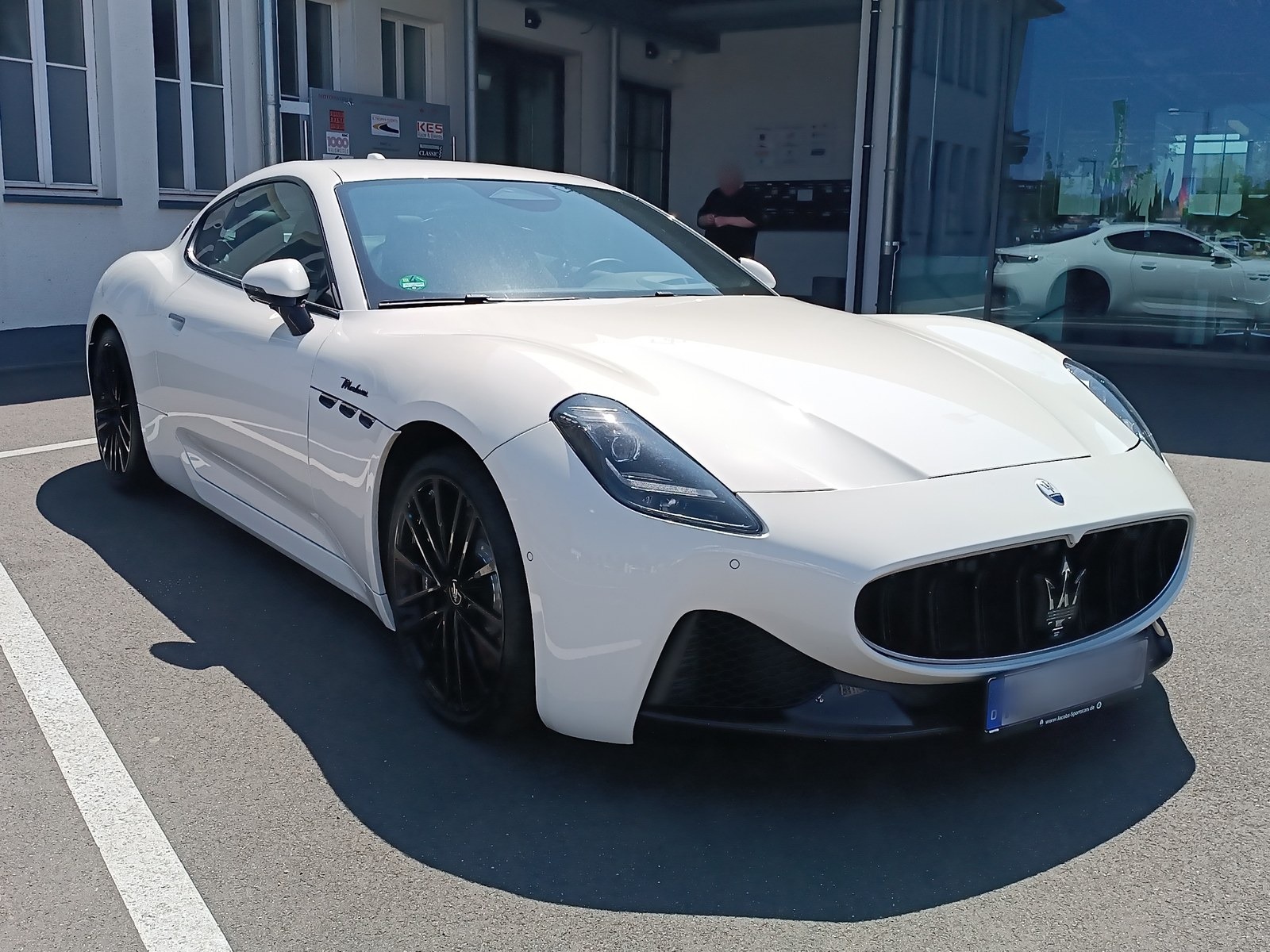 Maserati GranTurismo bianca, vista anteriore di tre quarti nel piazzale di un concessionario