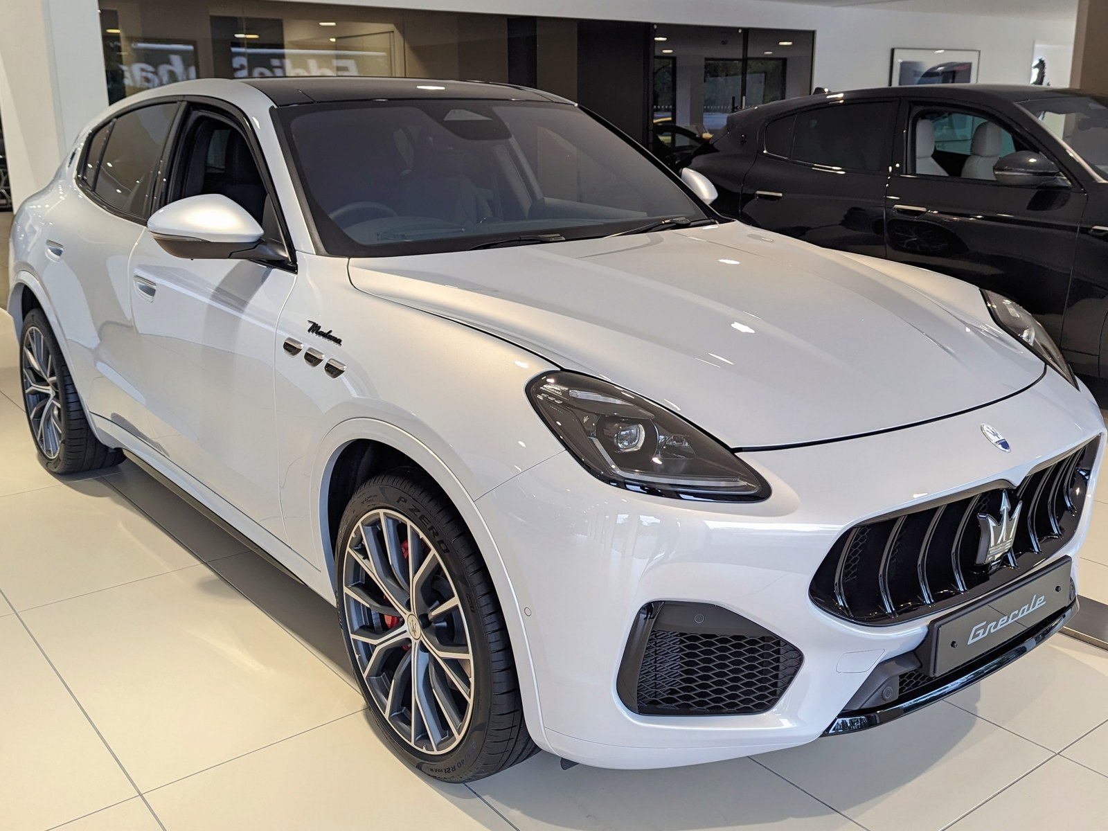 Maserati Grecale bianca con tetto nero, vista anteriore di tre quarti in un salone