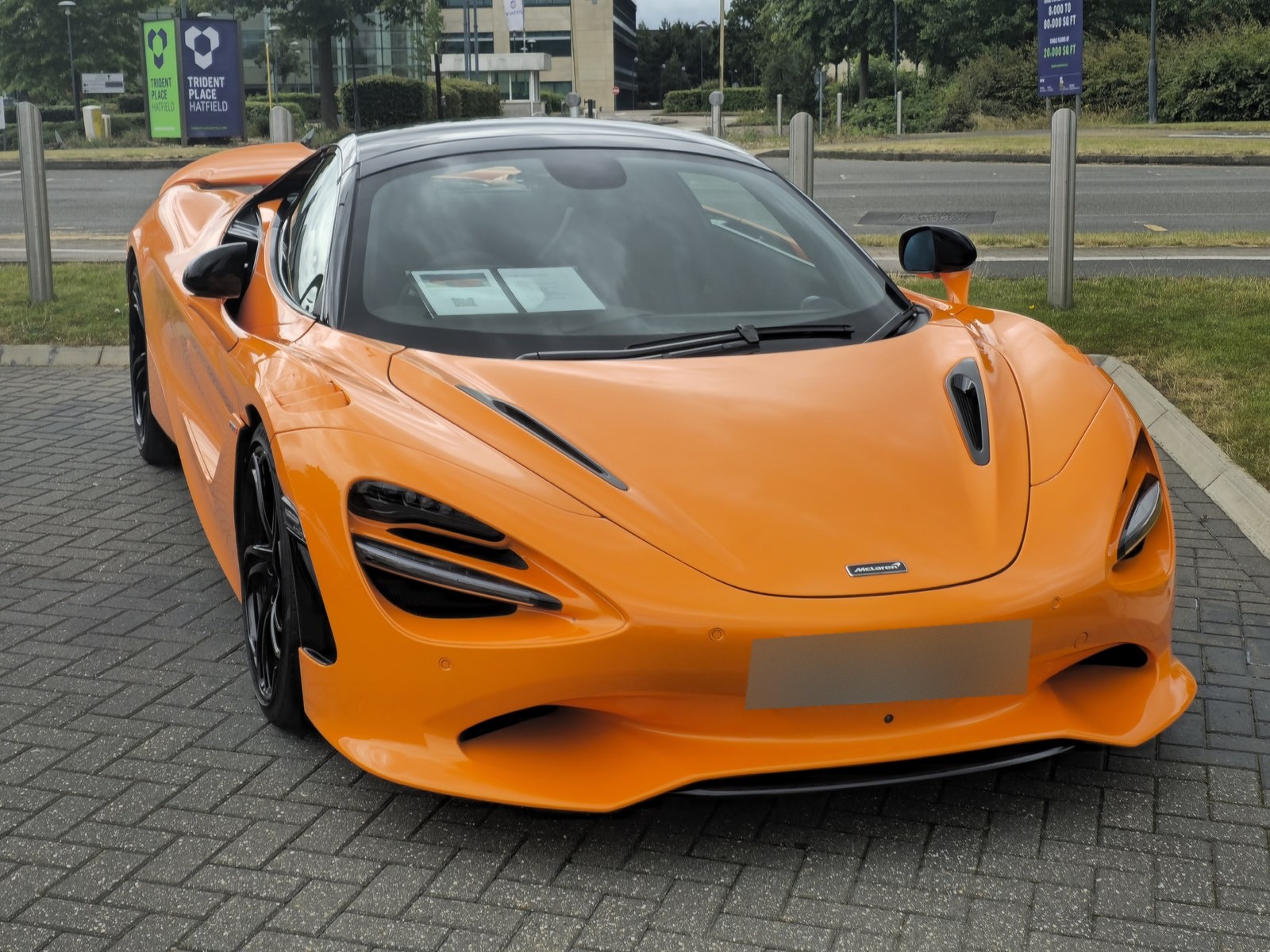 McLaren 750S arancione, vista anteriore di tre quarti in un parcheggio