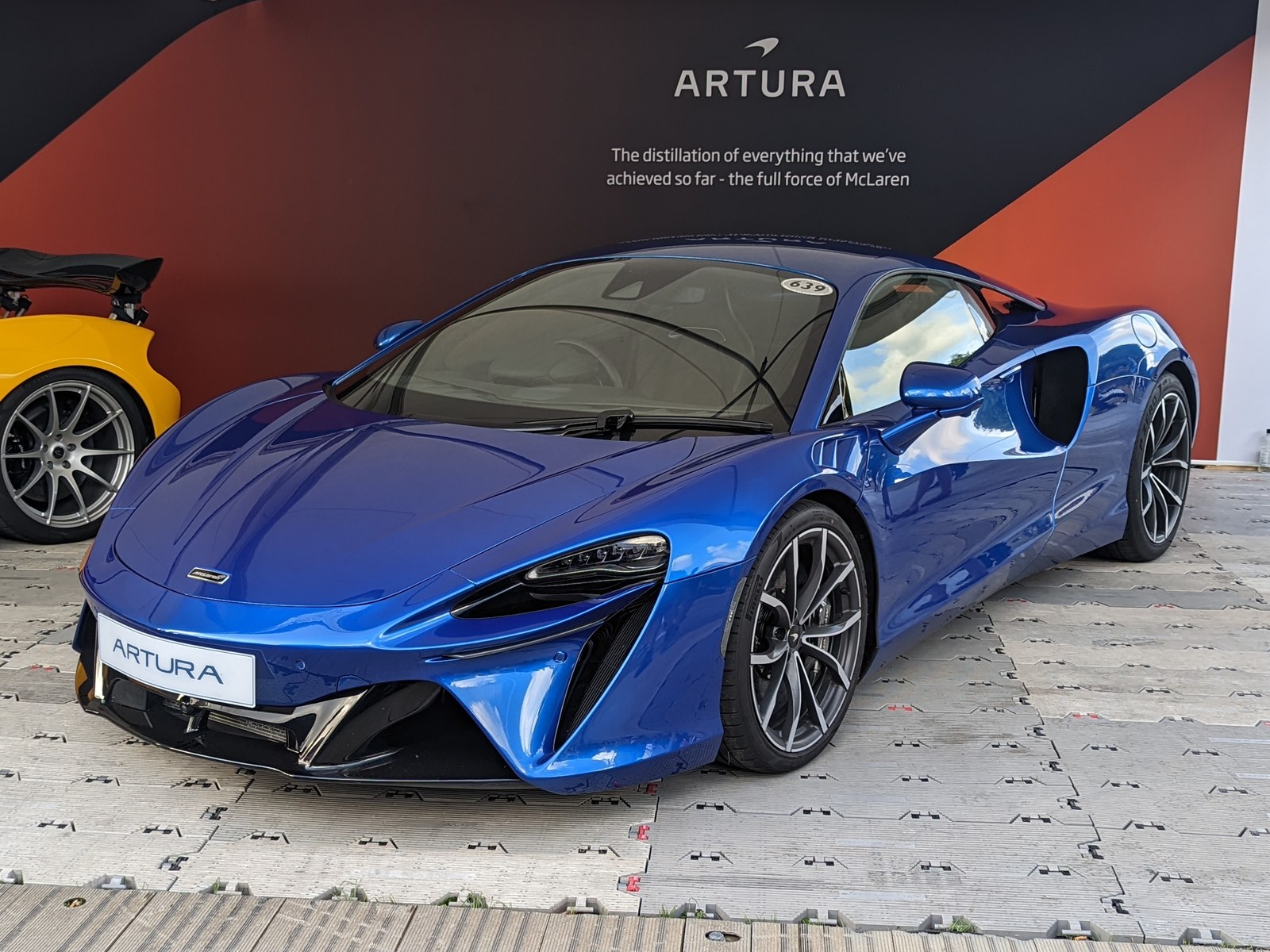 McLaren Artura blu, vista anteriore di tre quarti su uno stand espositivo
