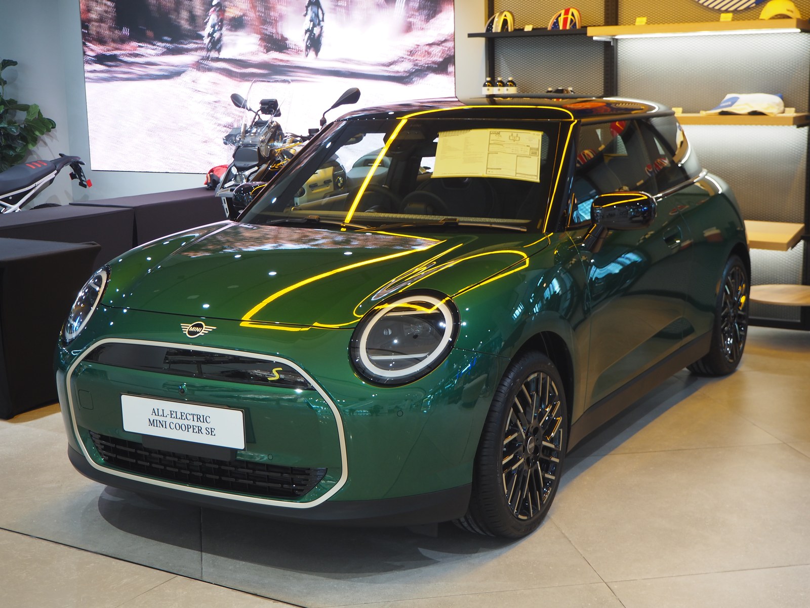 Mini Cooper SE elettrica verde, vista anteriore di tre quarti in un salone