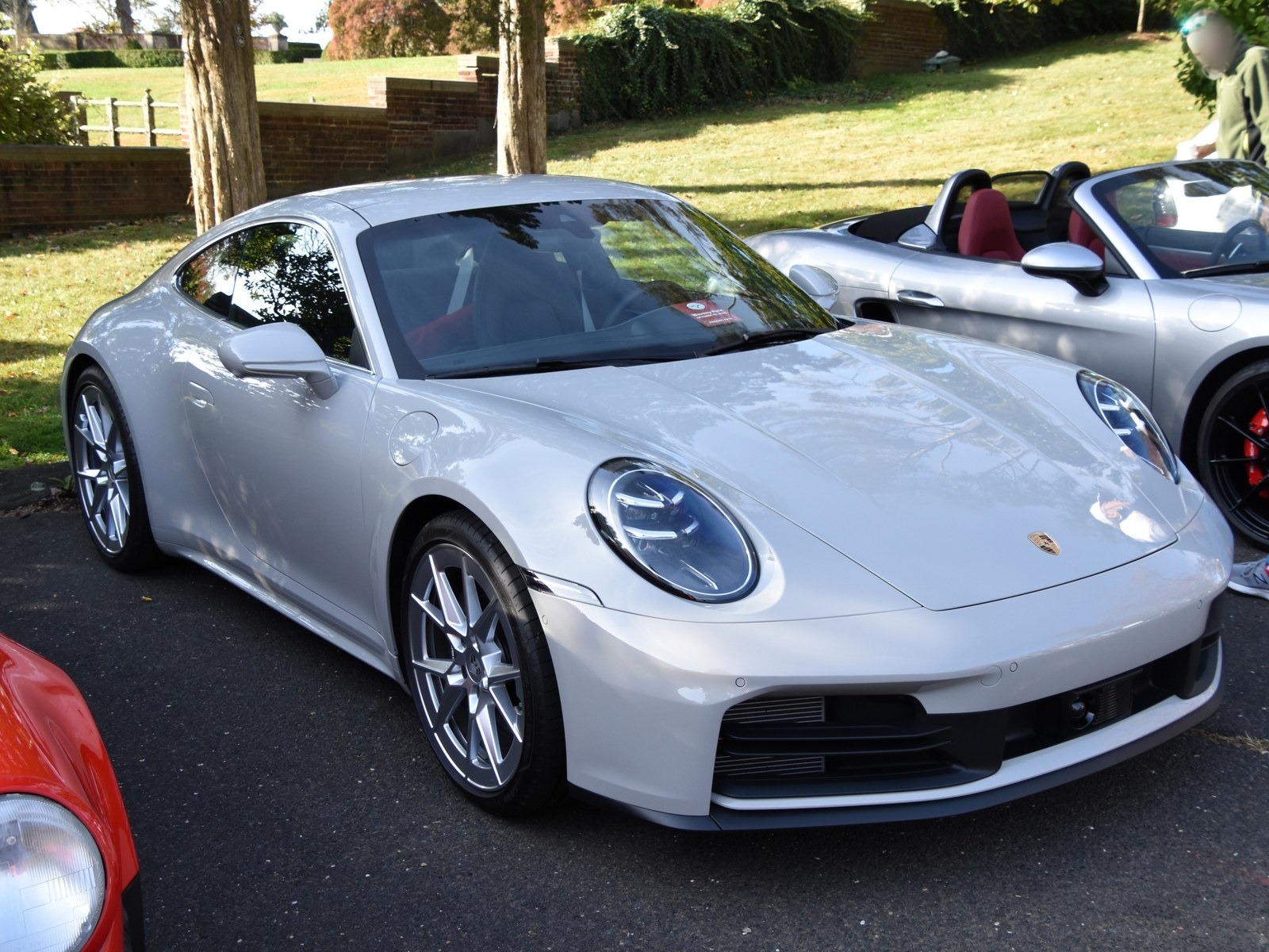 Porsche 911 Carrera grigio chiaro, vista anteriore di tre quarti a un raduno