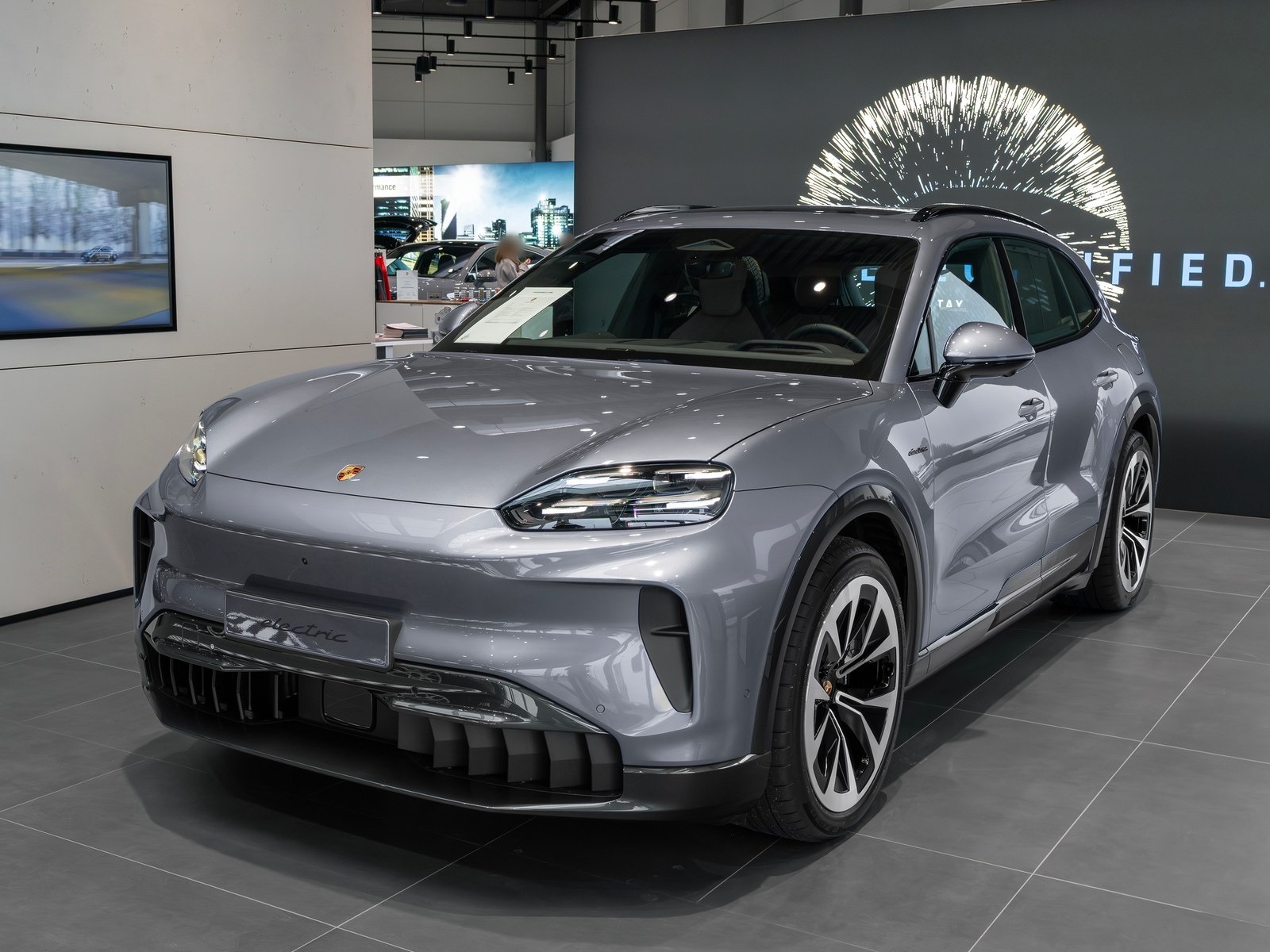 Porsche Cayenne Electric grigia, vista anteriore di tre quarti in un salone