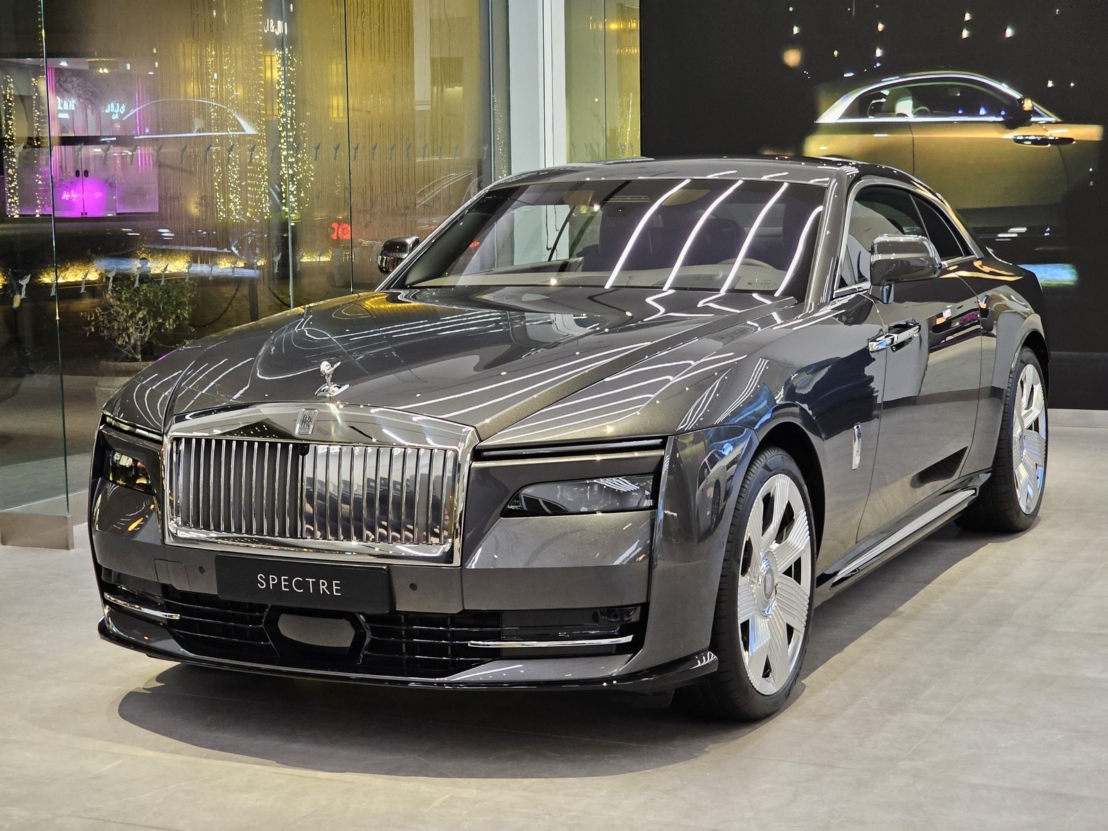 Rolls-Royce Spectre grigio antracite, vista anteriore di tre quarti in uno showroom